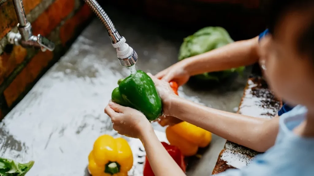 Manos de un Niño pequeño lavando alimentos como parte de la crianza consciente